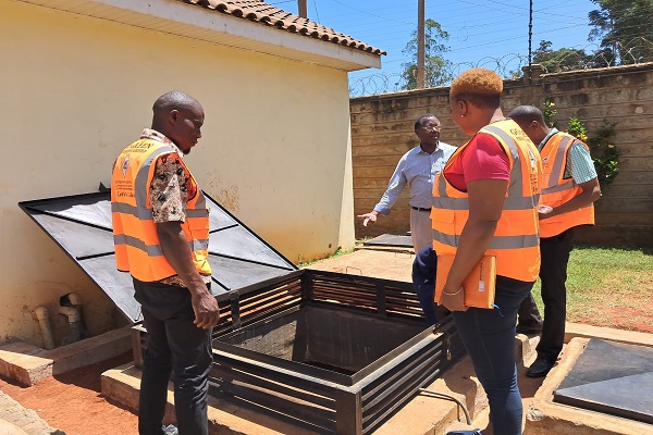 Field staff inspecting a solar dryer with a customer